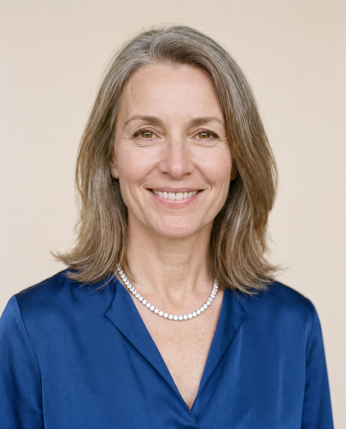 Woman in a royal-blue silk blouse wearing a moissanite tennis necklace